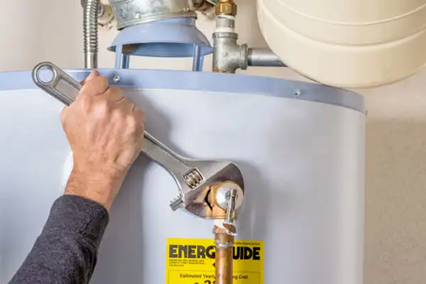 %Title% | Any Hour Services- Electric, Plumbing, Heating &Amp; Air A person uses a large adjustable wrench to tighten a fitting on a water heater with an Energy Guide label.
