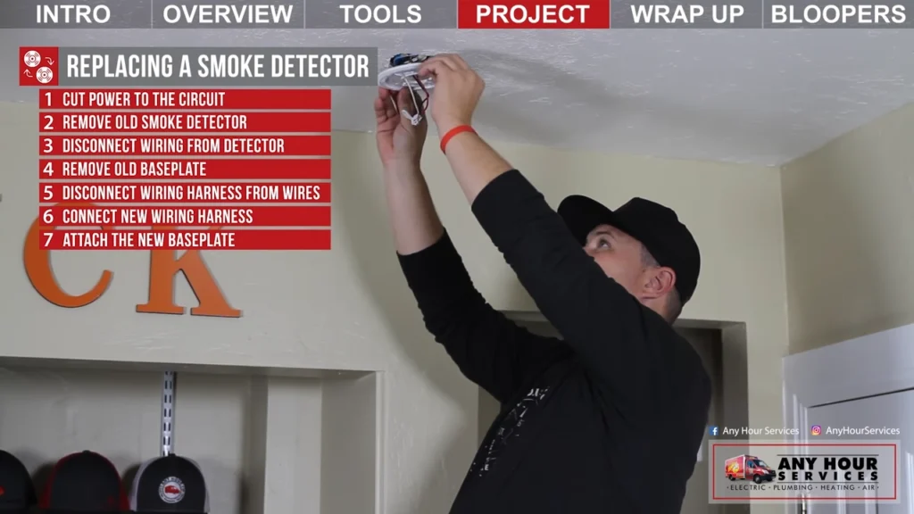 %Focuskw% | Any Hour Services Man standing on chair replaces a smoke detector on the ceiling; a step-by-step instruction list for replacing a smoke detector is shown on the left.