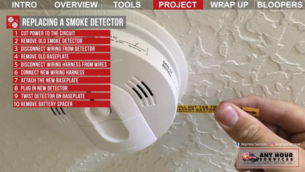 %Focuskw% | Any Hour Services A person measures the distance from a ceiling-mounted smoke detector with a tape measure; installation steps are listed on a red instruction panel.