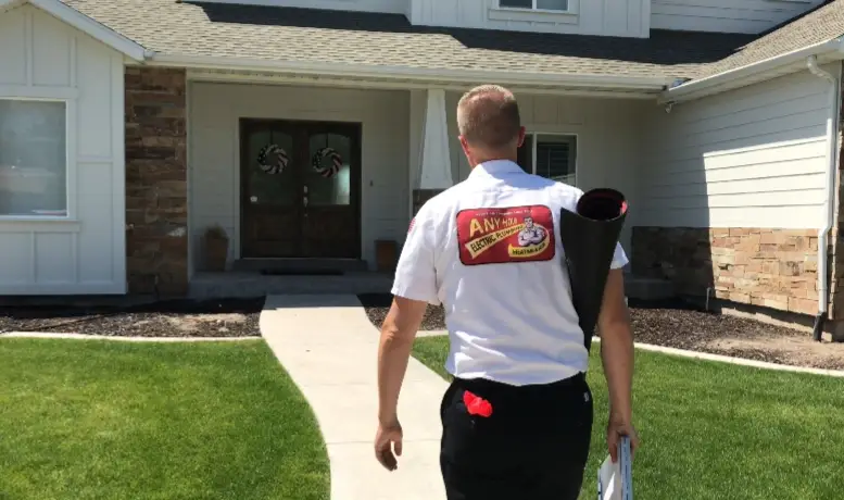 any hour technician walks toward a customer's front door with his back to the camera, the any hour logo is visible on the back of his uniform