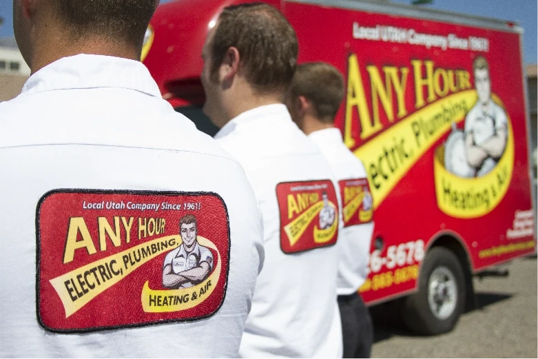 any hour technicians standing in a line with their backs toward the camera, while all standing in front of an any hour work truck