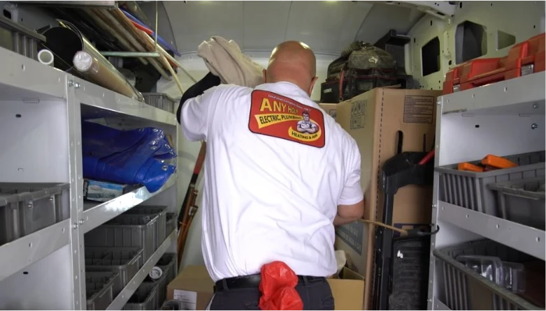 any hour technician searching the back of his truck, any hour logo visible on the back of his uniform.