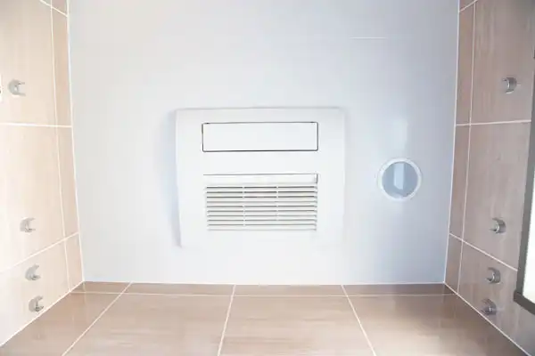 A tiled shower in Salt Lake City features multiple wall-mounted spray jets, a central white ventilation unit for efficient dehumidifier installation, and a round opening on the right wall.