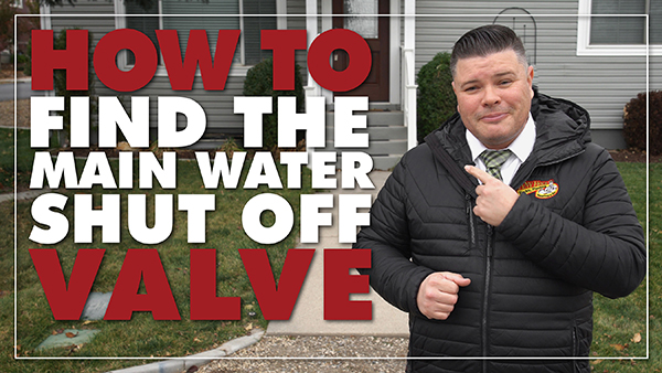 A man in a black jacket stands in front of a house, pointing to text that reads "How to locate water main shut off valve.