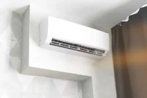 %Imagetitle% | Any Hour Services- Electric, Plumbing, Drains, Heating &Amp; Air Wall-mounted air conditioner installed near the ceiling in a modern Salt Lake City room, next to a window with dark curtains—perfect for efficient cooling and easy mini-split repair in UT.