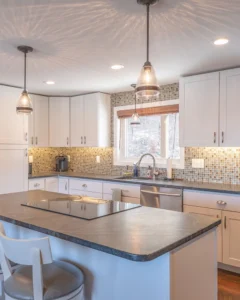 Modern kitchen with white cabinets, mosaic tile backsplash, pendant lights, a center island with seating, and stainless steel appliances. Enjoy efficient plumbing and easy drain cleaning, while sunlight streams through a window above the sink.