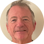 %Focuskw% | Any Hour Services Older man with short gray hair and a slight smile, standing in front of a plain light-colored wall.