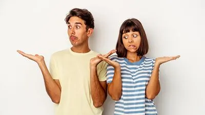 %Imagetitle% | Any Hour Services Two people stand side by side against a plain background, both raising their hands and making confused facial expressions—perhaps puzzled by signs of water heater failure in their home.