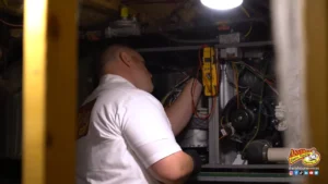 %Title% | Any Hour Services A technician in a white shirt works on wiring inside an open heating furnace under a bright overhead light.