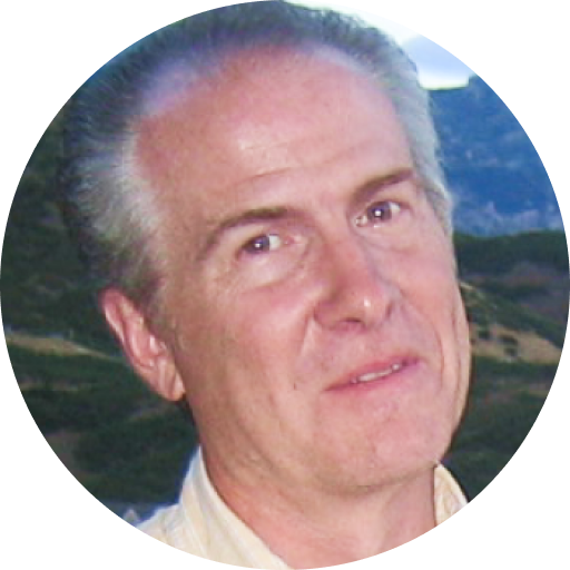 A middle-aged man with gray hair smiles slightly at the camera, outdoors with hills and greenery in the background, enjoying the fresh air during the Summer Sweepstakes.