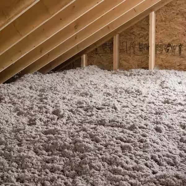 Professional loose-fill insulation installed between wooden rafters and joists in an attic by the Any Hour Services team.